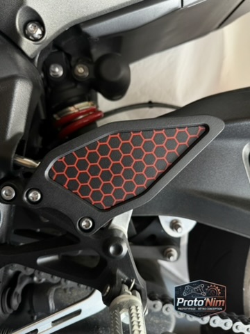 Protection de cheville Proto’Nim montée sur moto avec motif alvéoles rouge.