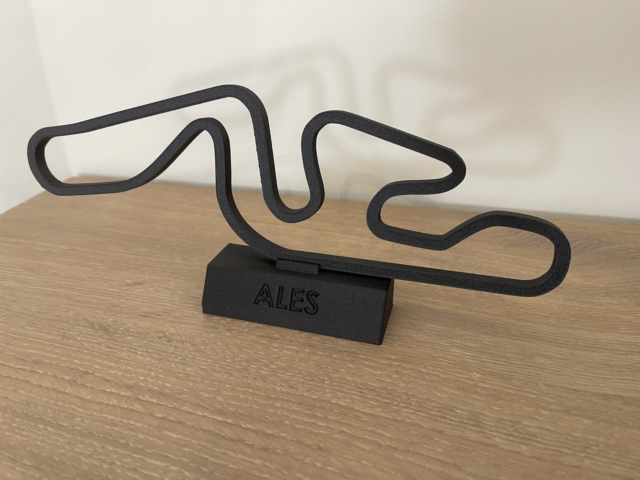 Objet décoratif imprimé en 3D représentant un tracé de circuit sur son socle.
